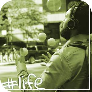 Junger Mann mit Bart jongliert Bälle und hat Kopfhörer auf.