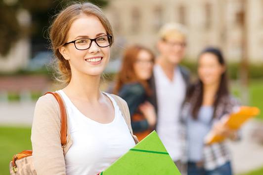 Studentin schaut lachend zum Fotografen. Im Hintergrund Gruppe mit drei Studierende.